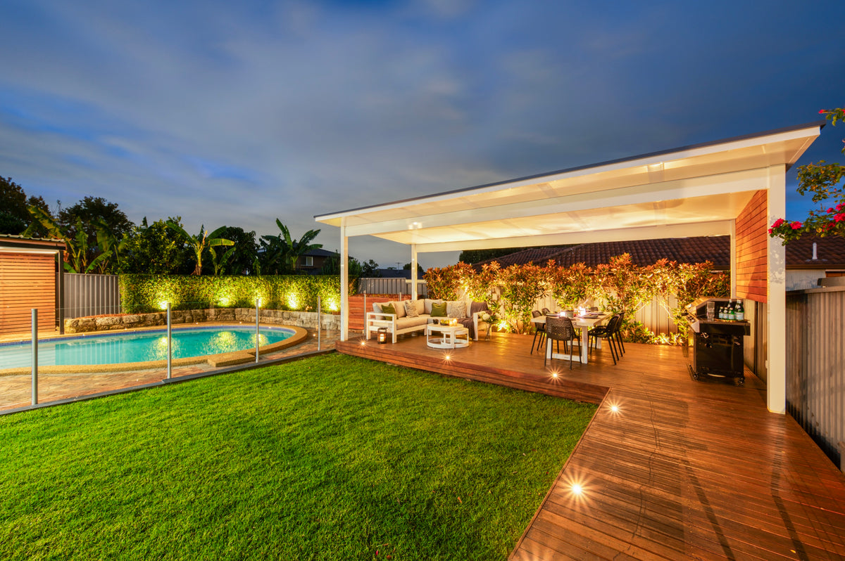 Freestanding patio beside a pool, lit up at dusk
