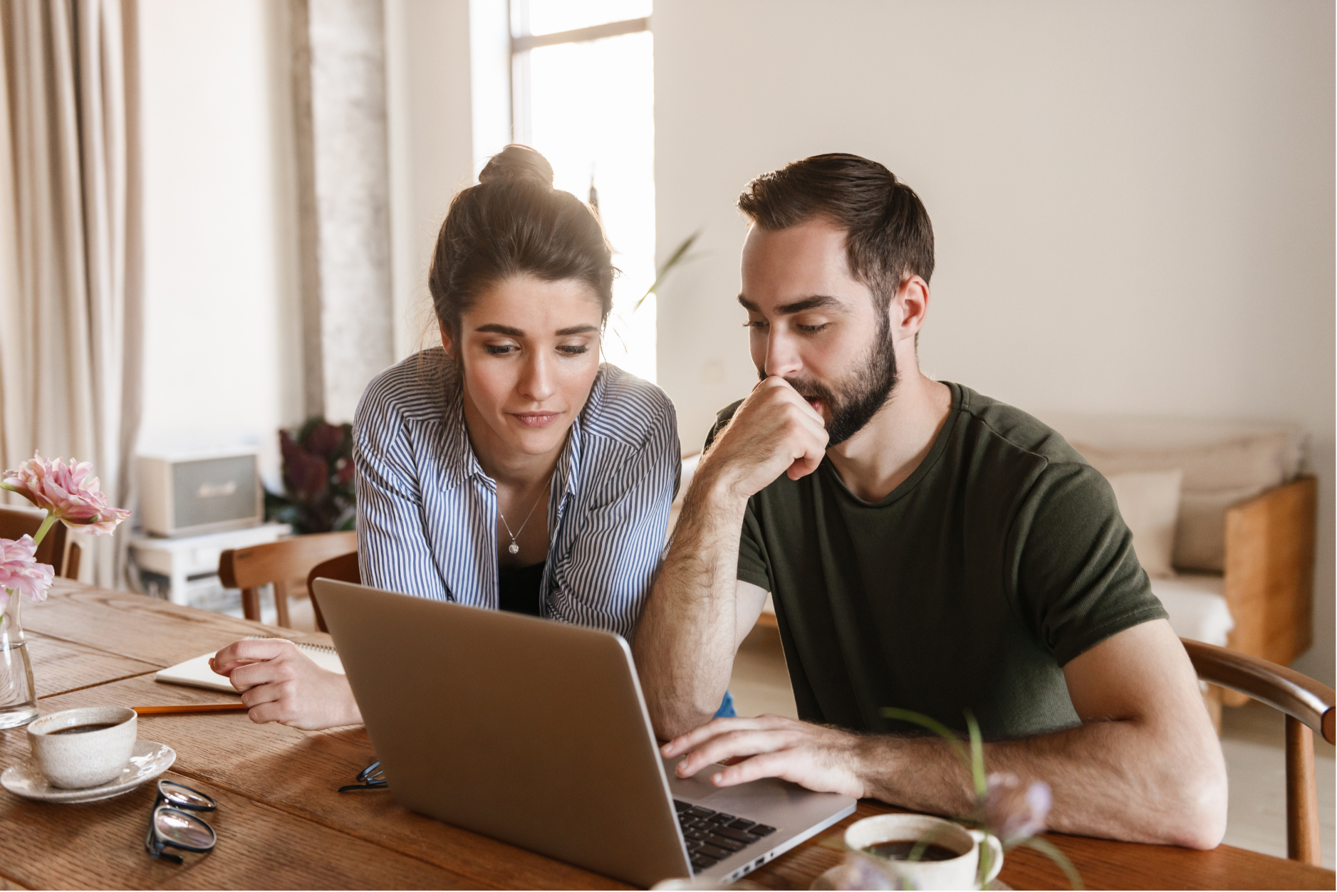 Two people working together on a laptop at a table.