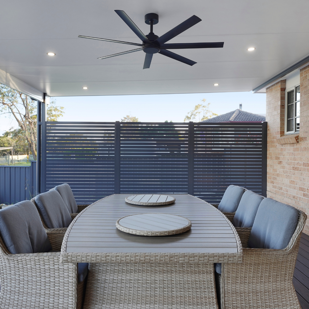 Outdoor patio area with a round table and chairs under a ceiling fan.