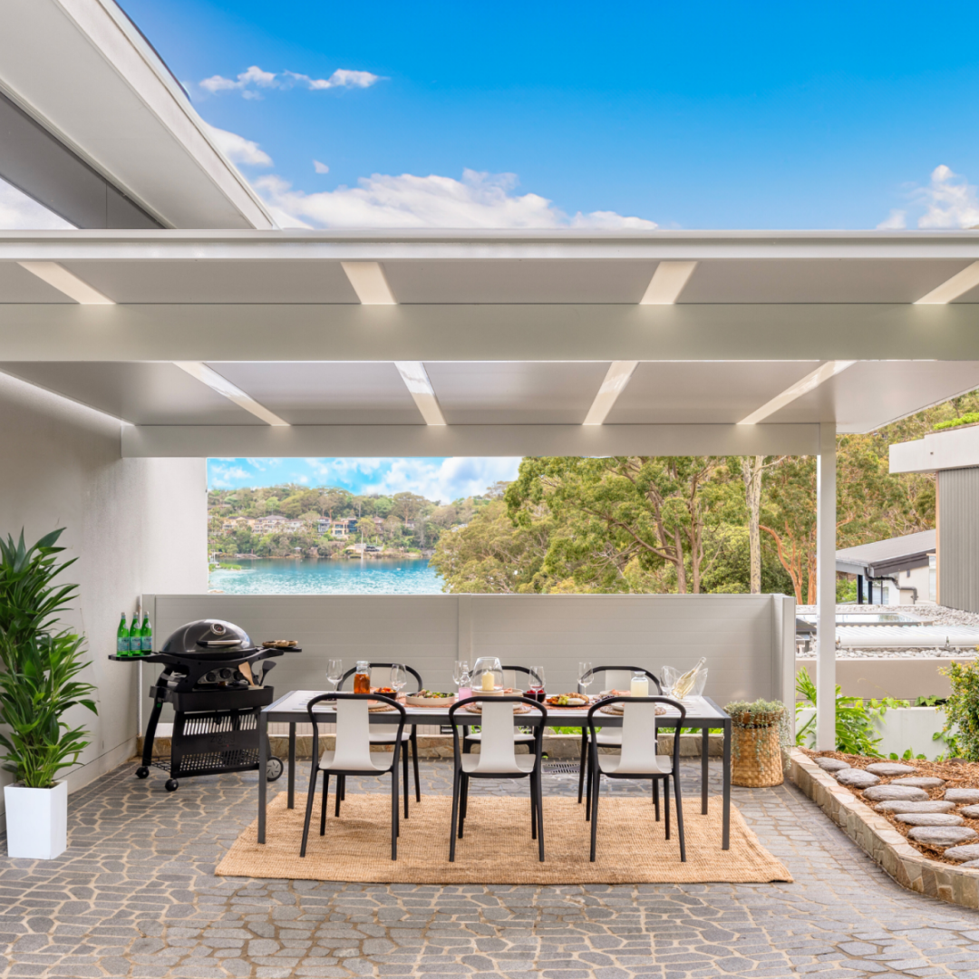Outdoor patio with dining table, chairs, and barbecue area with a scenic view.