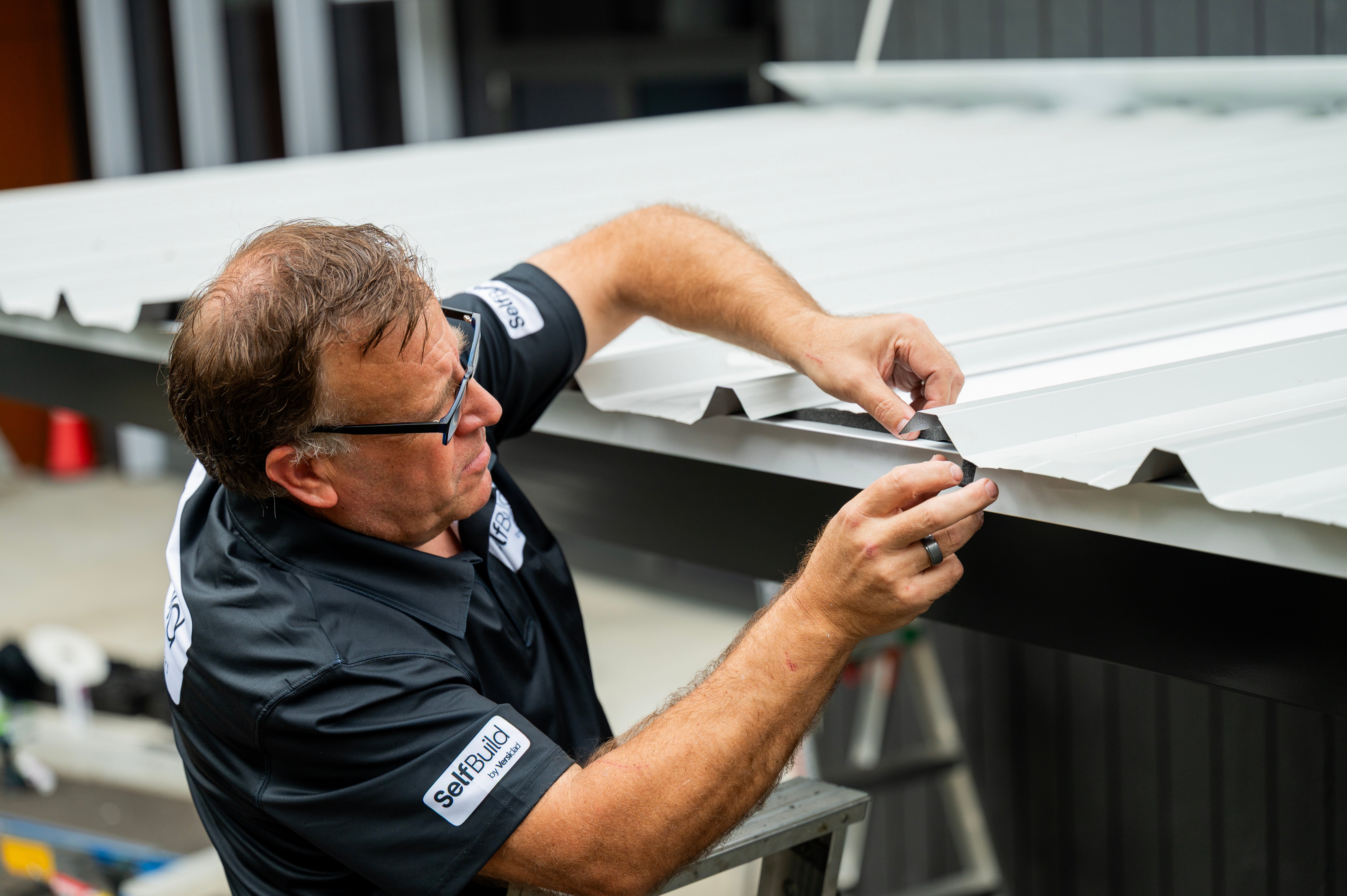 Man inspecting metal roofing panels in a workshop setting